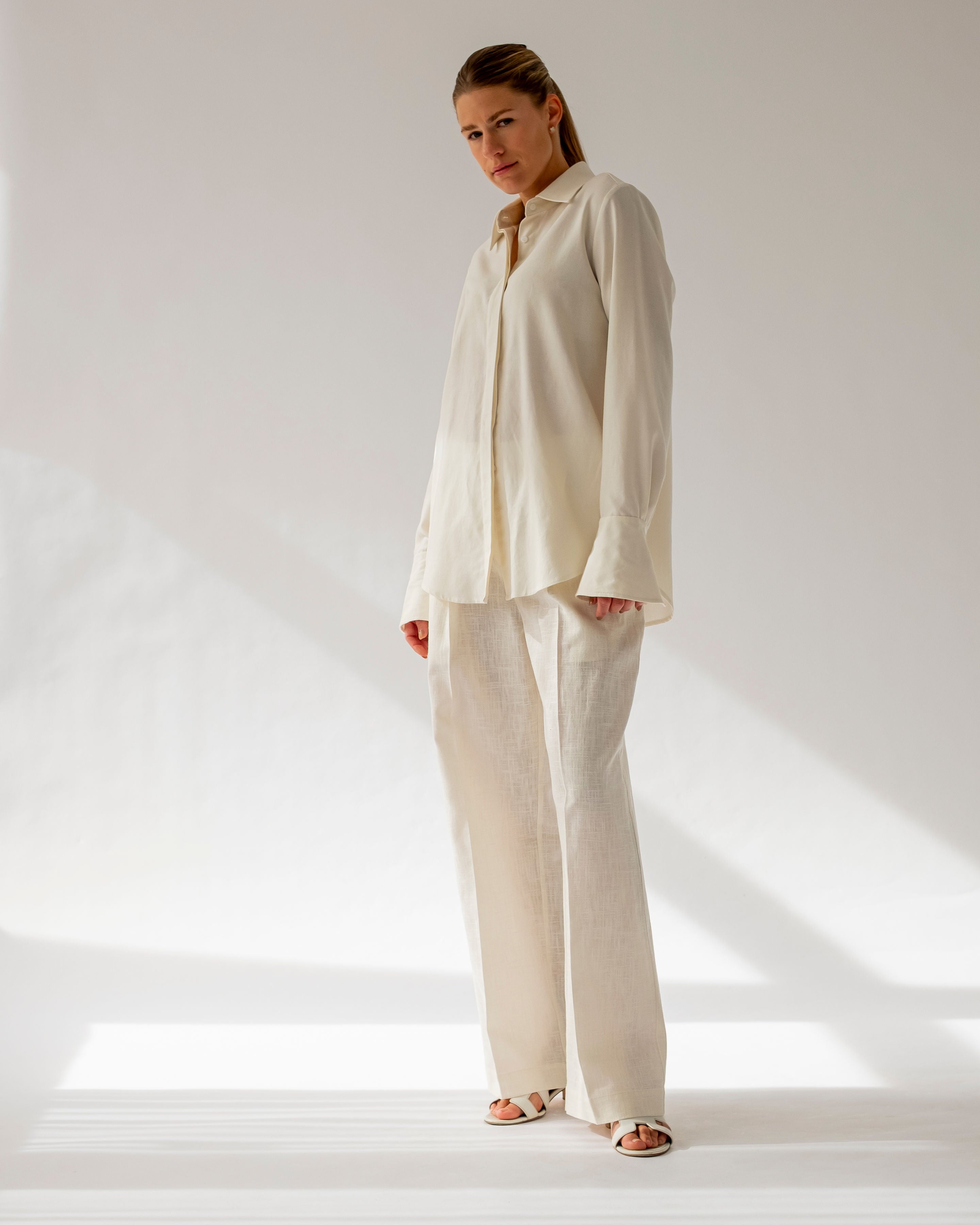 Woman wearing a white shirt and pants on a plain background